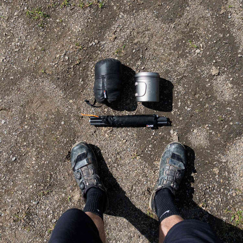 Blick auf das Bikepacking Zelt System mit Zubehör, auf felsigem Boden, mit Mountainbike und Campingausrüstung, für Outdoor-Touren geeignet