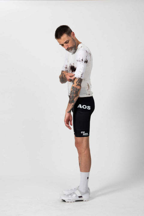 Mann trägt schwarze Fahrradhose mit weißen Buchstaben, steht seitlich, zeigt das Design der Fahrradhose, Tattoos sichtbar