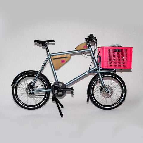 Compact Cargobike Flinc mit pinker Kiste und Rahmentaschen. Vielseitiges Mietrad für urbane Abenteuer und Transporte.