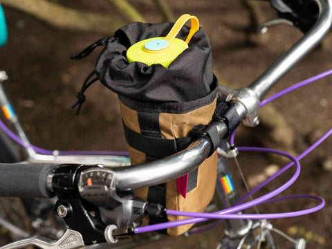 Gibby Lenker Tasche 1.75L in Braun am Fahrradlenker befestigt, mit Trinkflasche befüllt, ideal für sportliche Outdoor-Touren.