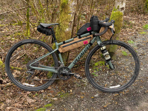 Gravelbike mit montierter Swift Industries / Hold Fast Frame Bag in Sandfarbe, ideal für Abenteuerfahrten durch Wald und Gelände.