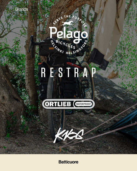 Ein voll bepacktes Fahrrad lehnt an einem Baum im Wald, umgeben von Logos bekannter Fahrradmarken: Pelago, Restrap, Ortlieb, KKS und Batticuore.