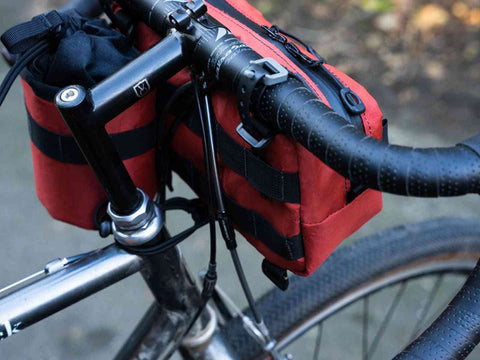 Rote Swift Industries Kestrel Handlebar Bag 2L mit Zubehör am Rennradlenker. Vielseitige Halterung für sportliche Radfahrer.
