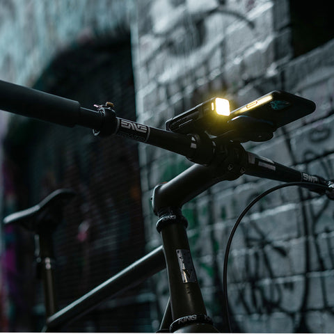 Leuchtendes Knog Blinder Frontlicht bei Dämmerung, montiert an urbanem Fahrrad. Perfekt für sichere Fahrten bei schlechten Lichtverhältnissen.