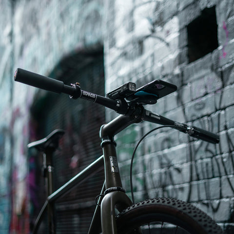 Knog Blinder Frontlicht am Fahrradlenker in urbaner Umgebung montiert. Teil des Knog Blinder Front & Rücklicht Sets für Stadtfahrten.