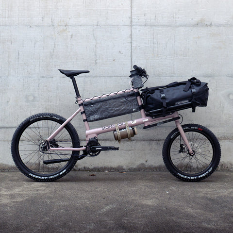 Fahrrad mit Gepäckträger und Tasche vor grauer Wand