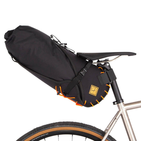 Restrap Satteltasche 18l/14l mit orangefarbener Verschnürung, montiert am Fahrrad für maximale Stabilität.