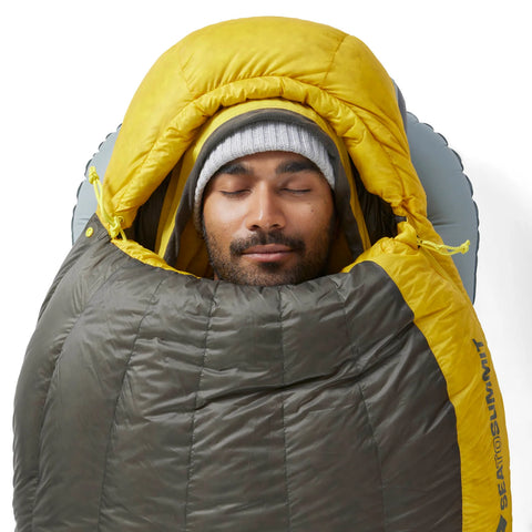 Person liegt im Sea to Summit Spark Daunenschlafsack Unisex, isolierend und komfortabel für kalte Nächte beim Camping.
