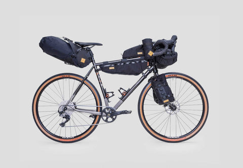Gravelbike mit kompletter Bikepacking-Ausrüstung, inklusive Rahmentasche, Lenkertasche, Satteltasche und Gabeltaschen, auf weißem Hintergrund.