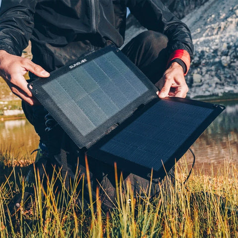 Person hält tragbares Solarpanel im Freien, zeigt flexible, faltbare Solartechnologie mit hoher Effizienz, geeignet für Outdoor-Aktivitäten