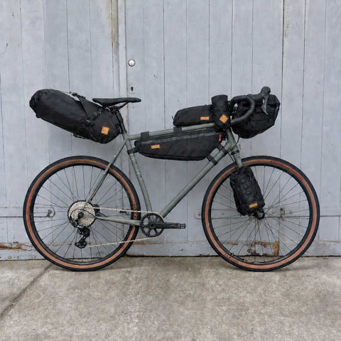 Graues Gravel-Bike mit schwarzen Packtaschen und Zubehör, 188-196cm Rahmen, für Bikepacking, mit mehreren Taschen für Abenteuer
