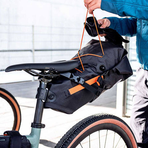 Montage der wasserdichten Ortlieb Seat-Pack Satteltasche 11L am Fahrradsattel, perfekt für Outdoor-Abenteuer und MTB-Touren.