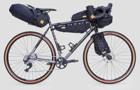 Gravelbike mit umfangreicher Bikepacking-Ausrüstung, darunter Rahmentasche, Lenkertasche, Satteltasche und Gabeltaschen, ideal für lange Touren und Abenteuerfahrten.