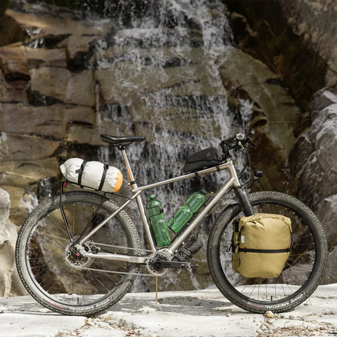 Fahrrad mit beige Gepäcktasche am Heck, vollgepackt mit Campingausrüstung, in einer natürlichen Outdoor-Umgebung