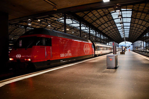 Roter SBB Intercity-Zug im Bahnhof Zürich Hauptbahnhof unter einem großen Glasdach, bereit zur Abfahrt auf einem leeren Bahnsteig bei schwachem Licht.